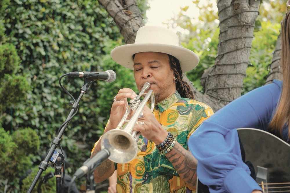 A trumpet player in a white hat, eyes closed