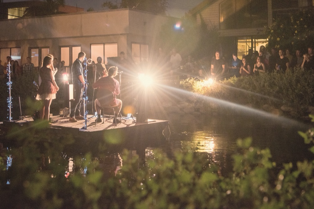 Musicians on a raft on a canal at night, lit by lanterns